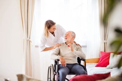 A woman is helping an older man in a wheelchair.