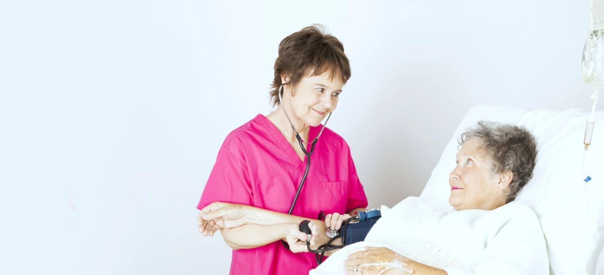 A woman in pink scrubs is holding a pair of scissors.