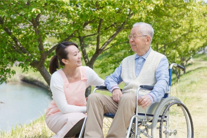 A woman sitting next to an older man in a wheelchair.