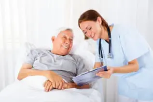 A nurse is showing an elderly man something