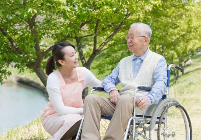 A woman sitting next to an older man in a wheelchair.